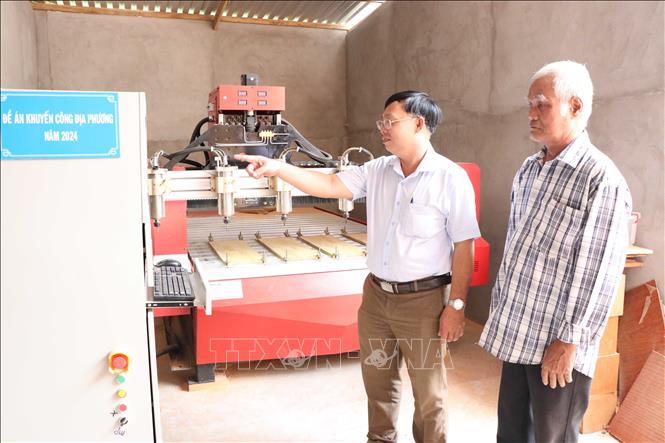 Ông Huỳnh Ngọc Xuân (trái), Giám đốc Trung tâm Khuyến công và Xúc tiến thương mại Trà Vinh nghiệm thu máy  tiện gỗ CNC tại hộ kinh doanh Thạch Phan - Phanh, thị trấn Cầu Kè, huyện Cầu Kè. Ảnh: Thanh Hòa - TTXVN