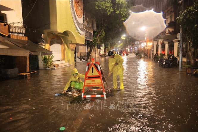 Công nhân Xí nghiệp thoát nước số 1 Hà Nội tích cực khơi thông dòng chảy đoạn ngập sâu trên phố Nguyễn Gia Thiều, quận Hoàn Kiếm. Ảnh: Hoàng Hiếu - TTXVN