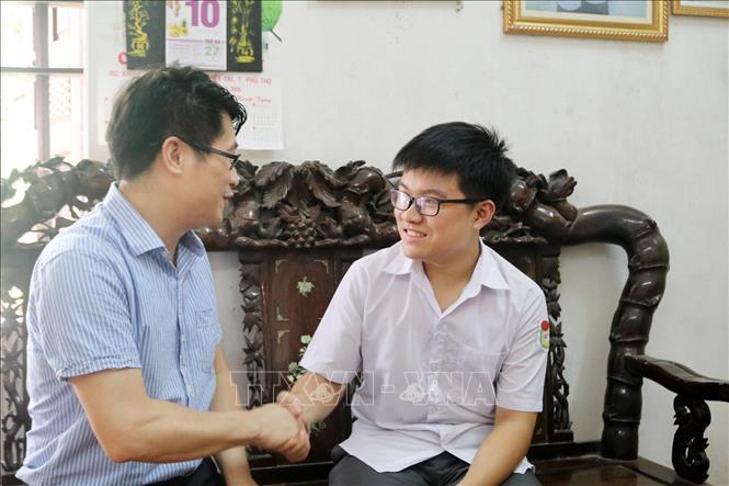 Trong ảnh: Thầy chủ nhiệm lớp chuyên toán Kiều Đình Minh chúc mừng em Hoàng Đức Thuận. Ảnh: Trung Kiên - TTXVN