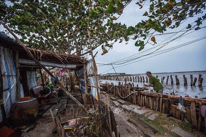 Trong ảnh: Bà Bành Thị Hía, ở ấp Cây Gõ, xã Vân Khánh Tây, huyện An Minh, tỉnh Kiên Giang ngày ngày sống chung cùng tuổi già và sóng gió, triều cường đến từ biển Tây. Bà Hía là hộ dân có mặt từ khi lập Ấp. Ngôi nhà của bà trước đây nằm sâu trong đất liền, nhưng qua thời gian biển xâm thực vào đất liền, căn nhà giờ đã nằm ra sát mép biển. Không người thân, bà chấp nhận đối mặt với thiên nhiên bởi việc di dời đến một nơi ở mới với bà thật sự là bất khả thi. Ảnh: Trọng Đạt - TTXVN