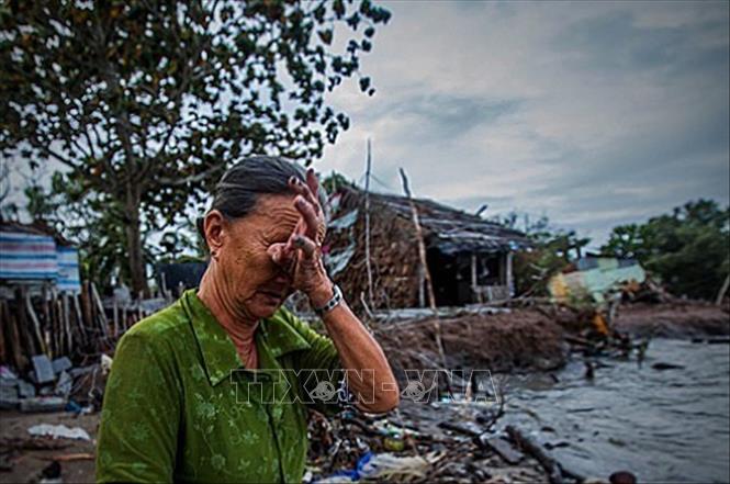 Trong ảnh: Bà Bành Thị Hía, 78 tuổi, một mình sống ở ấp Cây Gõ, xã Vân Khánh Tây, huyện An Minh (tỉnh Kiên Giang) không cầm được nước mắt mỗi khi nghĩ đến viễn cảnh phía trước. Phía sau lưng Bà Hía là căn nhà của bà, trước đây còn nằm sâu trong đất liền, nhưng qua thời gian biển xâm thực vào đất liền, căn nhà giờ đã nằm ra sát mép biển Tây tiềm ẩn đầy nguy hiểm, bất trắc. Không người thân, bà chấp nhận đối mặt với thiên nhiên bởi việc di dời đến một nơi ở mới với bà thật sự là bất khả thi. Ảnh: Trọng Đạt - TTXVN