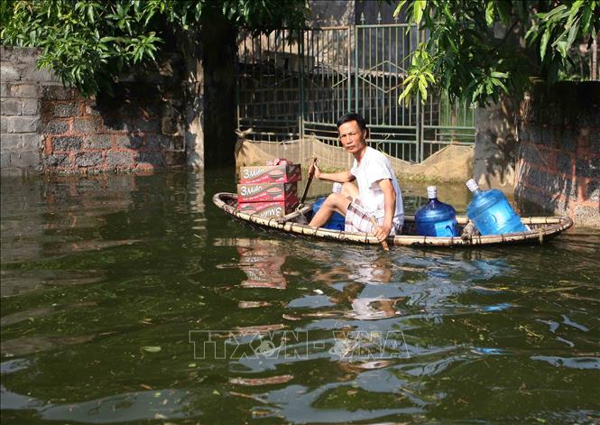 Trong ảnh: Người dân di chuyển bằng thuyền đi lấy lương thực và nước uống. Ảnh: Thanh Tùng - TTXVN