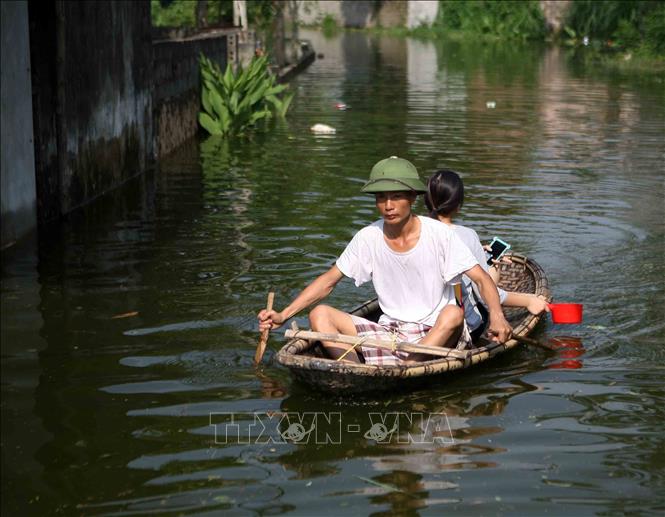 Trong ảnh: Người dân phải di chuyển bằng thuyền vì đường bị ngập lụt. Ảnh: Thanh Tùng - TTXVN