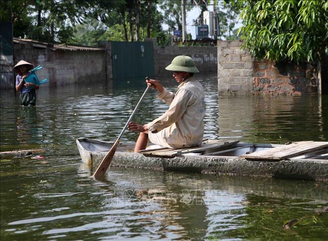 Trong ảnh: Người dân phải di chuyển bằng thuyền vì đường bị ngập sâu. Ảnh: Thanh Tùng - TTXVN