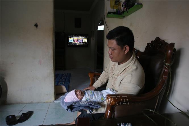 Trong ảnh: Bé gái Abidah Asian Games nằm trong lòng bố Yordania Denny tại nhà ở Palembang, Indonesia ngày 21/8. Ảnh: AFP/ TTXVN