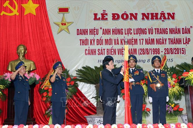 Trong ảnh: Trong ảnh: Chủ tịch nước Trương Tấn Sang gắn Danh hiệu ''Anh hùng lực lượng vũ trang nhân dân'' lên Lá cờ truyền thống của Cảnh sát biển Việt Nam, ngày 28/8/2015, tại Hà Nội. Ảnh: Nguyễn Khang – TTXVN