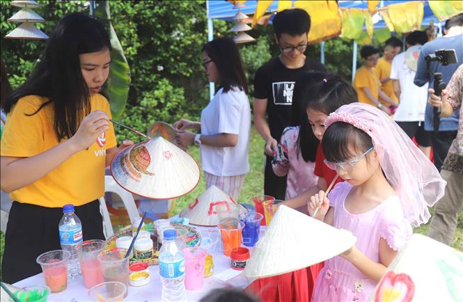 Trong ảnh: Các em bé tham gia vẽ tranh trên nón lá. Ảnh: Xuân Vịnh - Phóng viên TTXVN tại Singapore