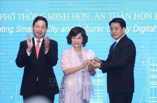 Photo: Chairman of the Hanoi People’s Committee Nguyen Duc Chung (R) presents a gift to Chairwoman of the World Information Technology & Services Alliance Yvonne Chiu (C). VNA Photo: Minh Quyết