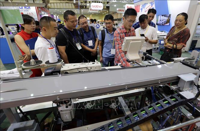 Trong ảnh: Khách tham quan gian trưng bày máy cắt may tự động tại triển lãm. Ảnh: Trần Việt - TTXVN