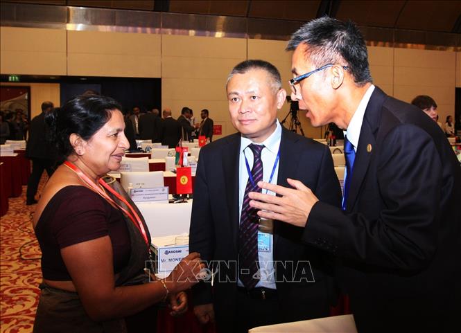Photo: Delegates discuss on the sidelines of the 7th symposium. VNA Photo
