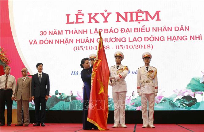 Trong ảnh: Chủ tịch Quốc hội Nguyễn Thị Kim Ngân gắn Huân chương Lao động hạng Nhì lên cờ truyền thống của Báo Đại biểu nhân dân. Ảnh: Văn Điệp -TTXVN