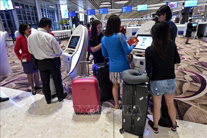Trong ảnh: Hành khách làm thủ tục bằng máy tự động tại sân bay quốc tế Changi ở Singapore. Ảnh: AFP/TTXVN