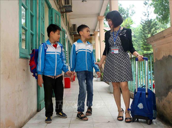 Trong ảnh: Cô giáo Trần Thị Thu Hiền giúp đỡ học sinh Nguyễn Khắc Hoàng Anh (bị khuyết tật cả vận động và trí tuệ) sau giờ tan học. Ảnh: Thanh Tùng-TTXVN