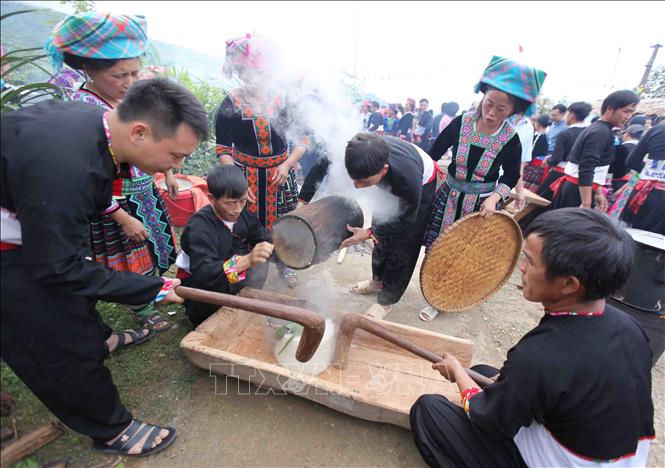 Photo: Cooked sticky rice is transfered to the hollow log, as strong men begin pounding the rice until it turns into sticky glutinous cake. VNA Photo: Quý Trung