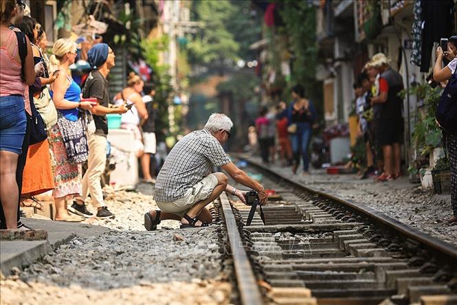 Trong ảnh: Một nhiếp ảnh gia đặt máy ảnh ở vị trí trên đường ray để ghi lại một khoảnh khắc đẹp khi đoàn tàu đến. Ảnh: Trọng Đạt - TTXVN