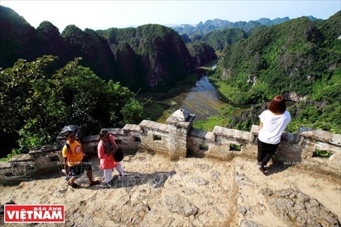 Al subir los escalones hacia la cima, los turistas disfrutan de una maravillosa vista del panorama de la hermosa tierra de Ninh Binh. 