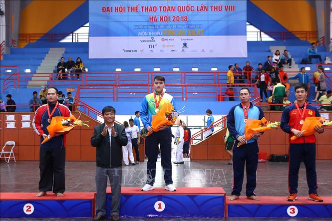 Trong ảnh: Ban tổ chức trao giải nội dung Đối kháng nam hạng 95kg: Lê Văn Toàn (Đà Nẵng, HCV), Huỳnh Tuấn Việt (Tiền Giang, HCB) và 2 VĐV Hoàng Văn Bắc (Hải Dương, HCĐ), Lê Văn Đại (Quân đội, HCĐ). Ảnh Minh Quyết – TTXVN