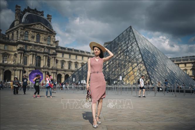 Trong ảnh: Khách du lịch chụp ảnh trước Bảo tàng Louvre ở Paris, Pháp. Ảnh: AFP/TTXVN