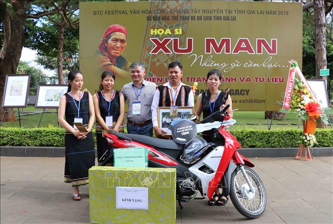 Trong ảnh: Gia đình cố họa sỹ Xu Man chụp ảnh lưu niệm với Ban tổ chức Triển lãm. Ảnh: Hồng Điệp - TTXVN.