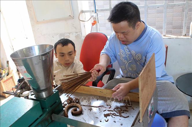 Trong ảnh: Thầy Phương (trái) vừa làm vừa hướng dẫn cho các nạn nhân da cam làm hương. Ảnh: Trần Lê Lâm - TTXVN