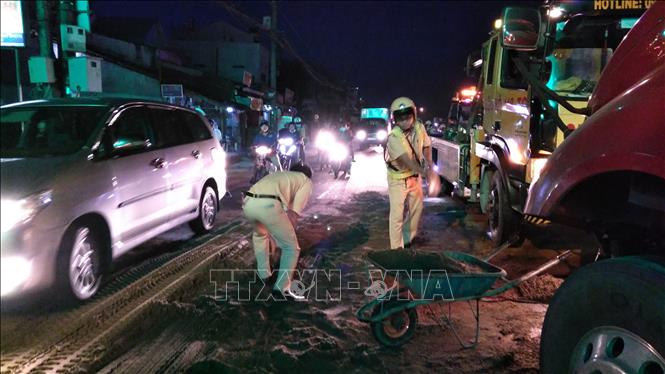 Trong ảnh: CSGT đổ cát lên phần dầu bị loang đổ trên đường. Ảnh: Nam Thái - TTXVN