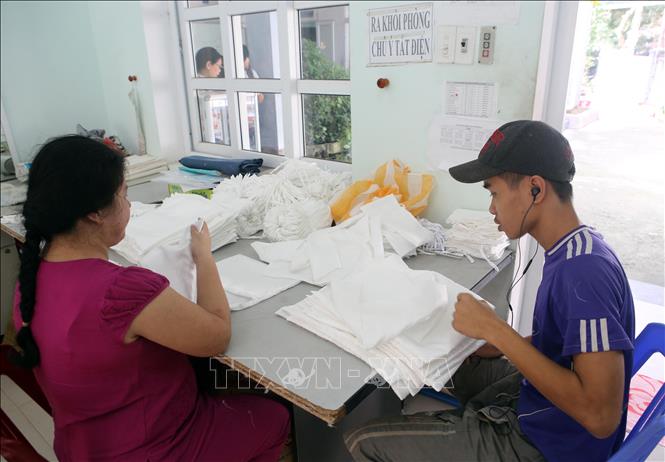 Trong ảnh: Nạn nhân da cam kiểm tra, hoàn thiện các sản phẩm may. Ảnh: Trần Lê Lâm - TTXVN