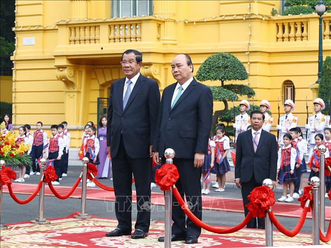 Trong ảnh: Thủ tướng Nguyễn Xuân Phúc và Thủ tướng Campuchia Samdech Techo Hun Sen trên bục danh dự, thực hiện nghi lễ chào cờ. Ảnh: Thống Nhất – TTXVN
