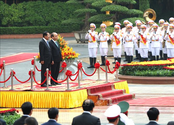 Trong ảnh: Thủ tướng Nguyễn Xuân Phúc và Thủ tướng Campuchia Samdech Techo Hun Sen trên bục danh dự, thực hiện nghi lễ chào cờ. Ảnh: Văn Điệp – TTXVN