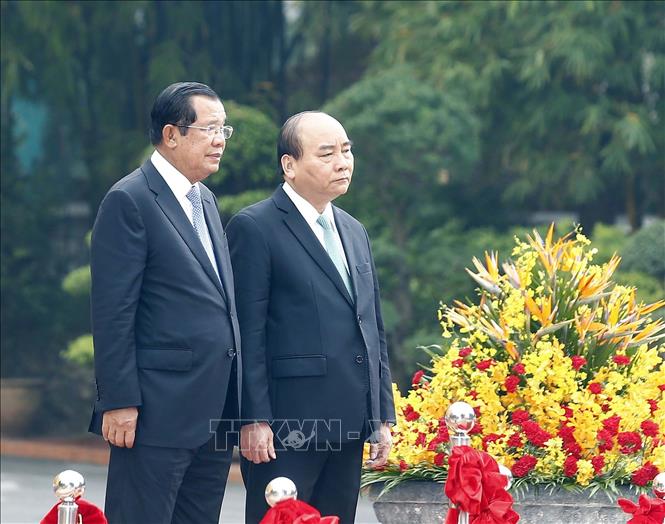 Trong ảnh: Thủ tướng Nguyễn Xuân Phúc và Thủ tướng Campuchia Samdech Techo Hun Sen trên bục danh dự, thực hiện nghi lễ chào cờ. Ảnh: Thống Nhất – TTXVN
