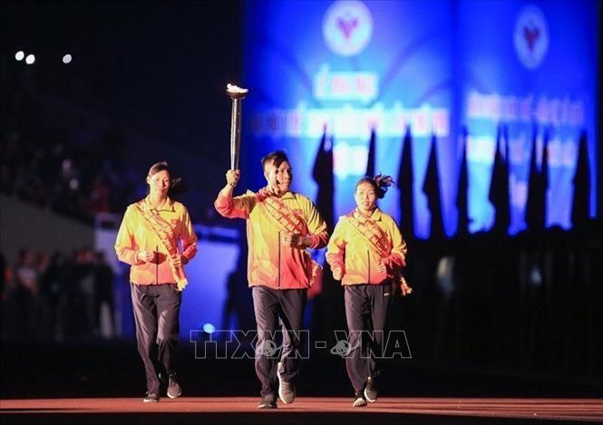 Trong ảnh: Xạ thủ Hoàng Xuân Vinh cùng 2 VĐV đạt thành tích xuất sắc là Bùi Thị Thu Thảo (điền kinh), Phạm Thị Thảo (Rowing) thực hiện nghi lễ rước đuốc được lấy từ Bảo tàng Hồ Chí Minh về thắp tại đài lửa của Đại hội. Ảnh: Trọng Đạt - TTXVN