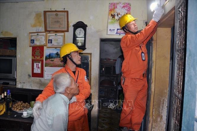 Trong ảnh: Lắp đặt bóng đèn tiết kiệm điện cho hộ gia đình chính sách trên địa bàn thành phố Hà Nội. Ảnh: TTXVN phát