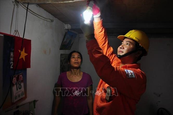 Trong ảnh: Lắp đặt bóng đèn tiết kiệm điện cho hộ gia đình chính sách trên địa bàn thành phố Hà Nội. Ảnh: TTXVN phát