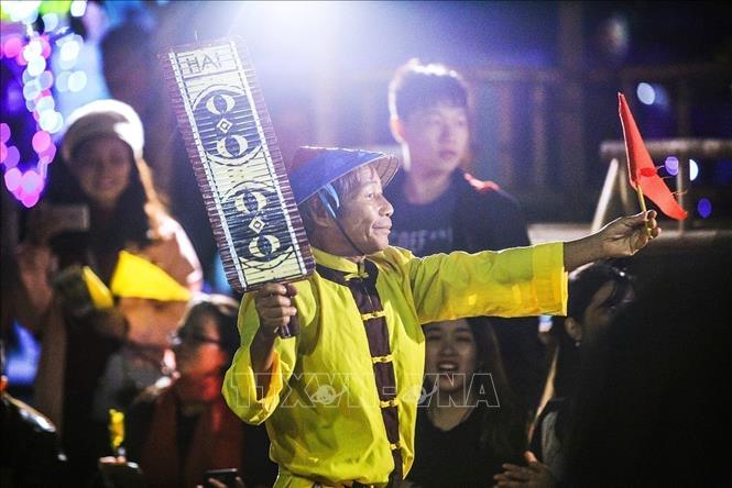 Photo: The game singer delivers a red flag to the cottage which has three cards that match the cards drawn from the bamboo poles. VNA Photo: Trọng Đạt