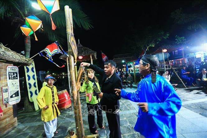 Photo: A tourist draws a card from a bamboo pole in the central house while participating in Bai Choi performance. VNA Photo: Trọng Đạt