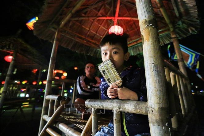Photo: A kid holds a playing card while participating in Bai Choi performance. VNA Photo: Trọng Đạt
