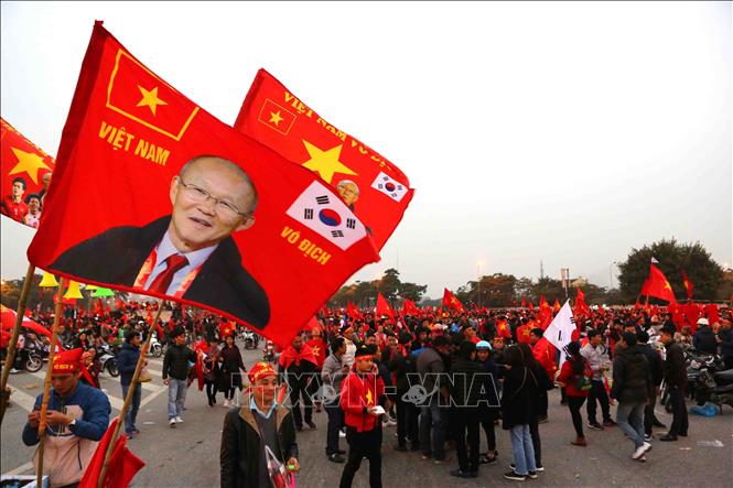 Photo: Vietnamese fans carry a flag with picture of Korean coach Park Hang-seo of the Vietnamese team. VNA Photo