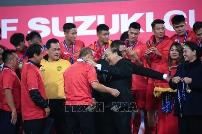 Photo: Prime Minister Nguyen Xuan Phuc hands over the trophy to Korean coach Park Hang-seo of the Vietnamese team. VNA Photo