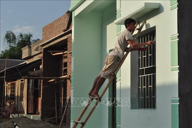 Trong ảnh: Anh Sa Văn Minh, ở bản Tủ, xã Sơn Lương, huyện Văn Chấn (Yên Bái) đang quét lớp sơn bên ngôi nhà mới của gia đình. Ảnh: Đinh Thùy - TTXVN