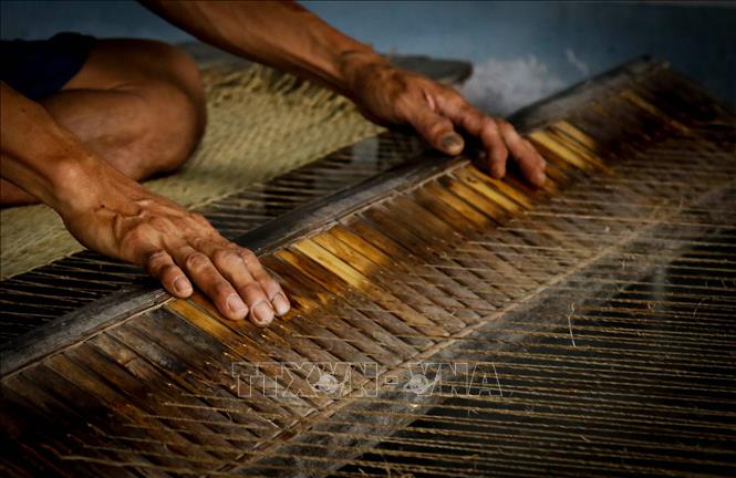 Trong ảnh: Nhiều hộ dân vẫn giữ phương pháp dệt chiếu thủ công bằng tay. Ảnh: Nam Thái - TTXVN