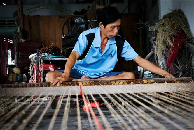 Photo: A craftsman weaves a sedge mat manually with his loom. VNA Photo: Nam Thái 