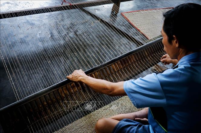Photo: A craftsman weaves a sedge mat manually with his loom. VNA Photo: Nam Thái