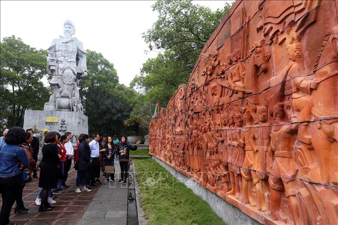 Trong ảnh: Du khách tham quan bức phù điêu ghi lại chiến công lịch sử được làm bằng đất nung cạnh Tượng đài Hưng Đạo Vương Trần Quốc Tuấn trong quần thể Đền Cao An Phụ. Ảnh: Danh Lam – TTXVN