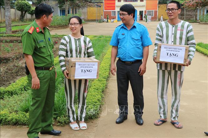 Trong ảnh: Phó Giám thị trại giam Kim Sơn Nguyễn Văn Phòng (ngoài cùng bên trái) và Chủ tịch hội Liên hiệp Thanh niên Việt Nam tỉnh Bình Định Lương Đình Tiên (thứ 3 từ trái sang) tặng quà, thăm hỏi, động viên các phạm nhân có thành tích cải tạo nổi bật. Ảnh: Quốc Dũng – TTXVN