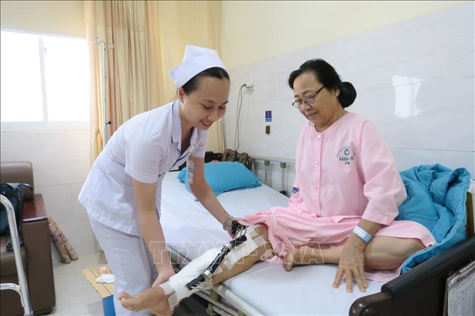 Trong ảnh: Bệnh nhân Trần Thị Kim Anh (bị gãy chân) đang được hỗ trợ vận động tại Bệnh viện Sài Gòn ITO Phú Nhuận. Ảnh: Đinh Hằng - TTXVN