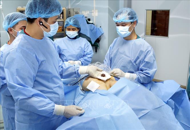 Trong ảnh: Thạc sĩ, bác sĩ Phan Hoàng Hiệp (trái) phẫu thuật nội soi tuyến giáp một lỗ và lấy ra một bệnh phẩm (ảnh chụp sáng 23/1/2019). Ảnh: Dương Ngọc - TTXVN