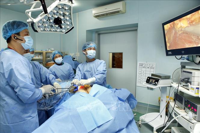 Trong ảnh: Thạc sĩ, bác sĩ Phan Hoàng Hiệp (trái) trực tiếp phẫu thuật nội soi tuyến giáp một lỗ cùng kíp mổ (ảnh chụp sáng 23/1/2019). Ảnh: Dương Ngọc - TTXVN