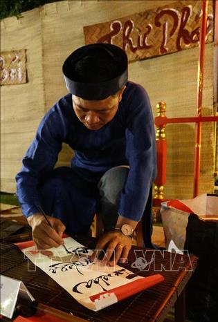 Trong ảnh: Biểu diễn viết thư pháp tại Phiên chợ quê ngày Tết. Ảnh: Ngọc Thành – TTXVN phát