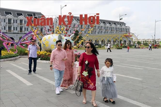 Trong ảnh: Du khách trên đường hoa xuân Khu đô thị Phú Cường, TP. Rạch Giá (Kiên Giang). Ảnh: Lê Huy Hải - TTXVN