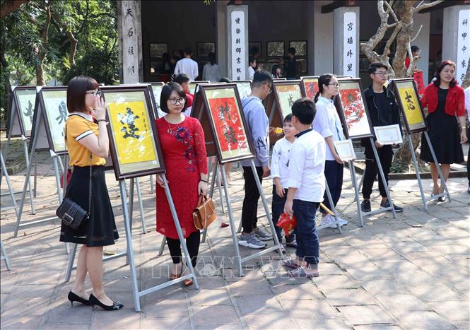 Trong ảnh: Người dân tham quan, chụp ảnh với các mẫu chữ Hán được treo khuôn viên Văn Miếu. Ảnh: Đinh Tuấn - TTXVN