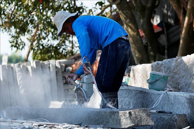 Trong ảnh: Người thợ dùng cưa máy để tạo rãnh trên đá. Ảnh: Hồng Đạt - TTXVN
